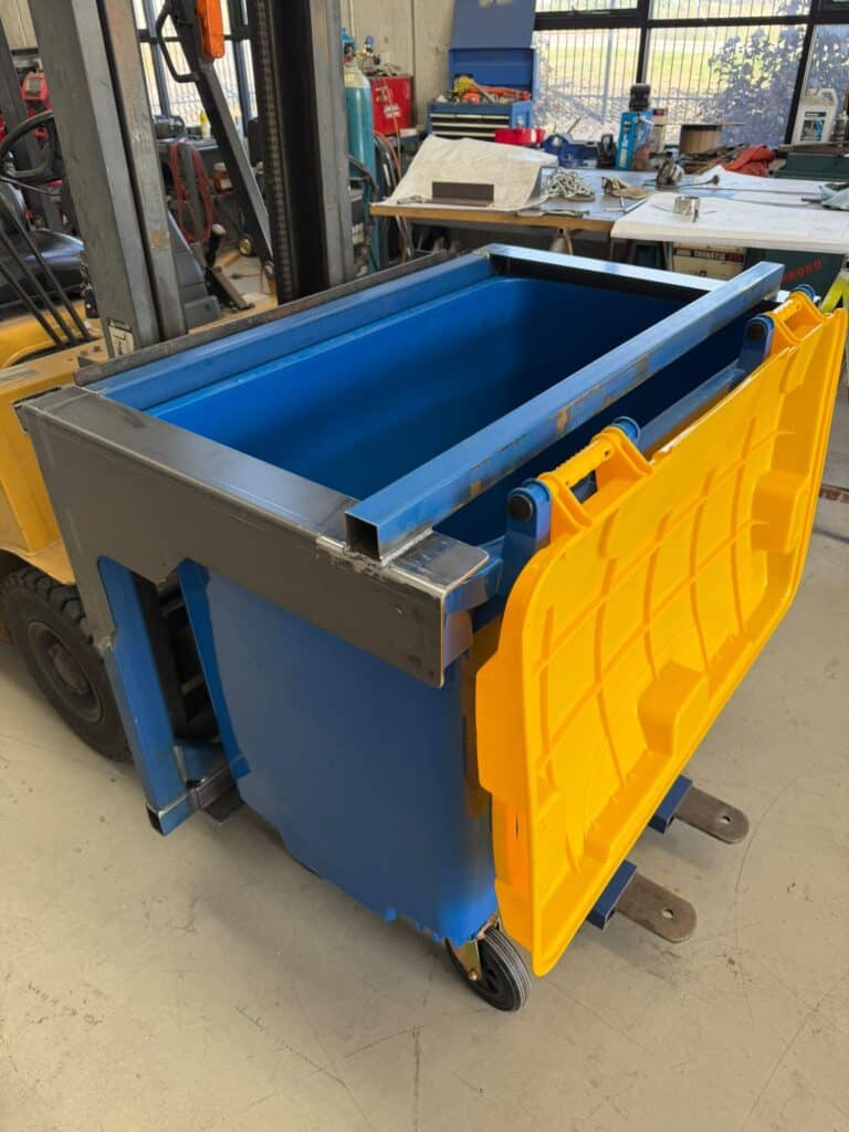 Custom Forklift Attachment Perth – Industrial Bin Fitment Custom forklift attachment Perth – fabricated steel frame fitted around a blue industrial bin with yellow lid